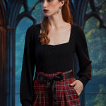 Woman wearing black ribbed knit square neck top with balloon sleeves and high-waisted plaid trousers