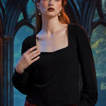 Woman wearing black square neck ribbed top with long balloon sleeves against gothic arched windows
