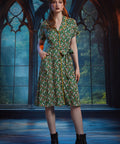 Woman wearing vintage-inspired button-front midi shirt dress with shawl collar, contrast piping, and pockets.
