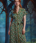 Woman wearing vintage-inspired midi shirt dress with whimsical pumpkin patch print, removable tie belt, and front pockets.