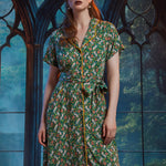 Woman wearing vintage-inspired midi shirt dress with whimsical pumpkin patch print, removable tie belt, and front pockets.