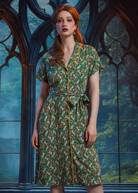 Woman wearing vintage-inspired midi shirt dress with whimsical pumpkin patch print, removable tie belt, and front pockets.