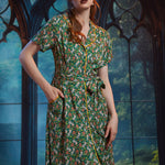 Woman wearing button-front shirt dress with pockets, removable belt, and woodland frog print.