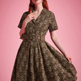 Woman wearing olive floral fit-and-flare dress with flowing full skirt