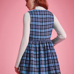 Back view of woman wearing a blue plaid sleeveless jumper dress showing fitted bodice, gathered waist and flared skirt