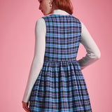 Back view of woman wearing a blue plaid sleeveless jumper dress showing fitted bodice, gathered waist and flared skirt