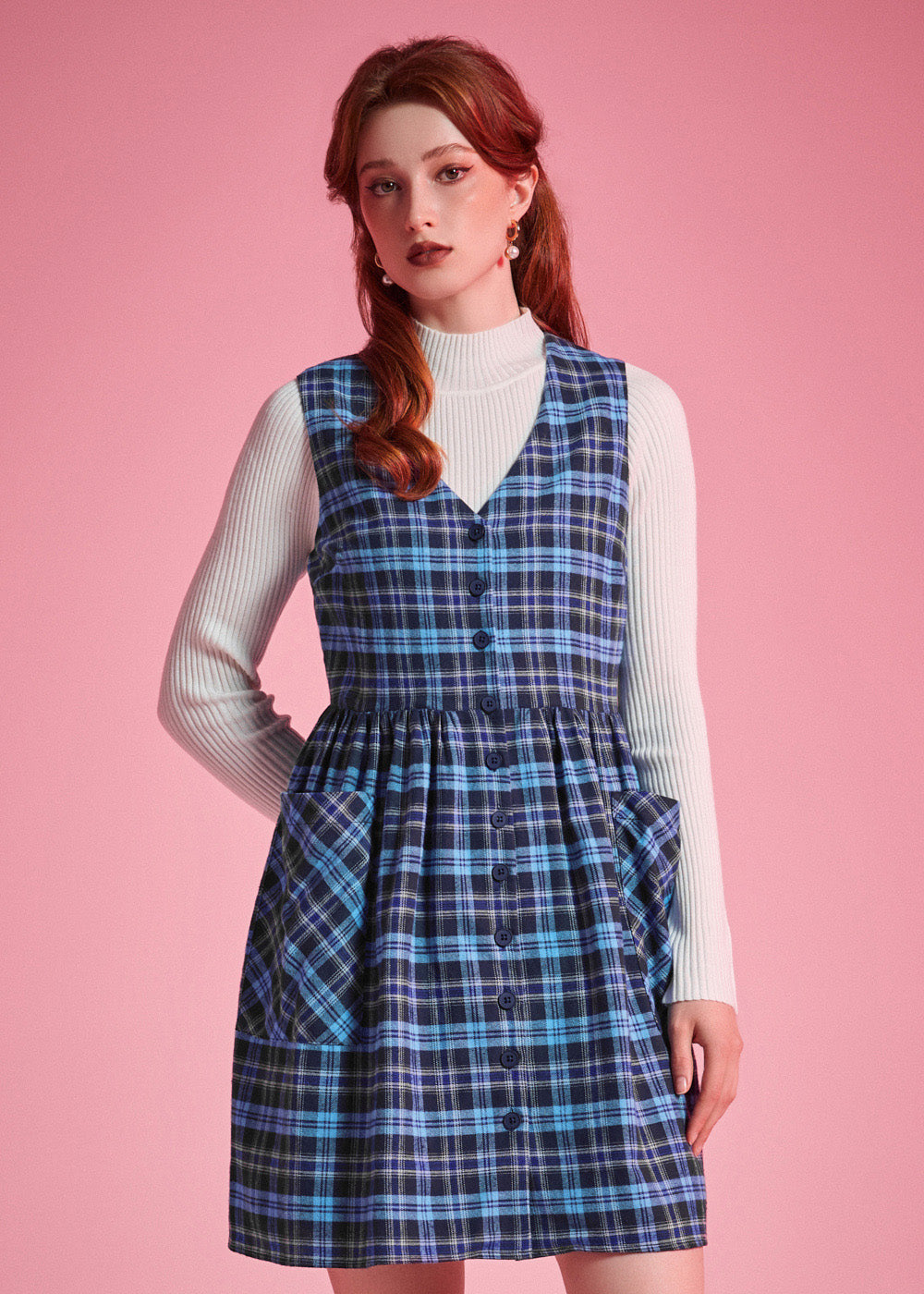 Front view of woman wearing a navy and aqua plaid cotton jumper dress with full button front and patch pockets