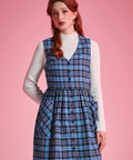Front view of woman wearing a navy and aqua plaid cotton jumper dress with full button front and patch pockets