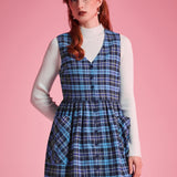 Front view of woman wearing a navy and aqua plaid cotton jumper dress with full button front and patch pockets