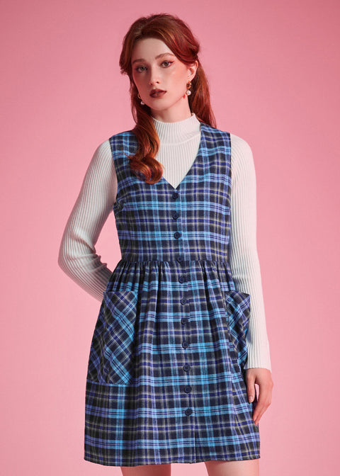 Front view of woman wearing a navy and aqua plaid cotton jumper dress with full button front and patch pockets