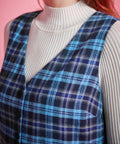 Close-up of blue plaid cotton jumper dress showing deep V-neckline, sleeveless bodice and navy aqua cream plaid