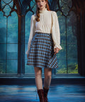 Full-length view of woman wearing a vintage-inspired blue plaid flare skirt with an ivory blouse and burgundy lace-up boots