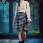 Full-length view of woman wearing a vintage-inspired blue plaid flare skirt with an ivory blouse and burgundy lace-up boots