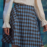 Front close-up of woman wearing the Sailor Flare Skirt in Study Blues with double button details and blue brown plaid pattern