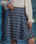 Front angled close-up of woman wearing a vintage-inspired plaid A-line skirt with double rows of sailor-style buttons