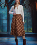 Full-length view woman wearing the ModCloth Turning the Page brown plaid midi skirt with white blouse, braided belt and burgundy boots
