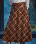 Angled view of woman wearing high-waisted brown plaid midi skirt with braided belt and bias-cut A-line silhouette