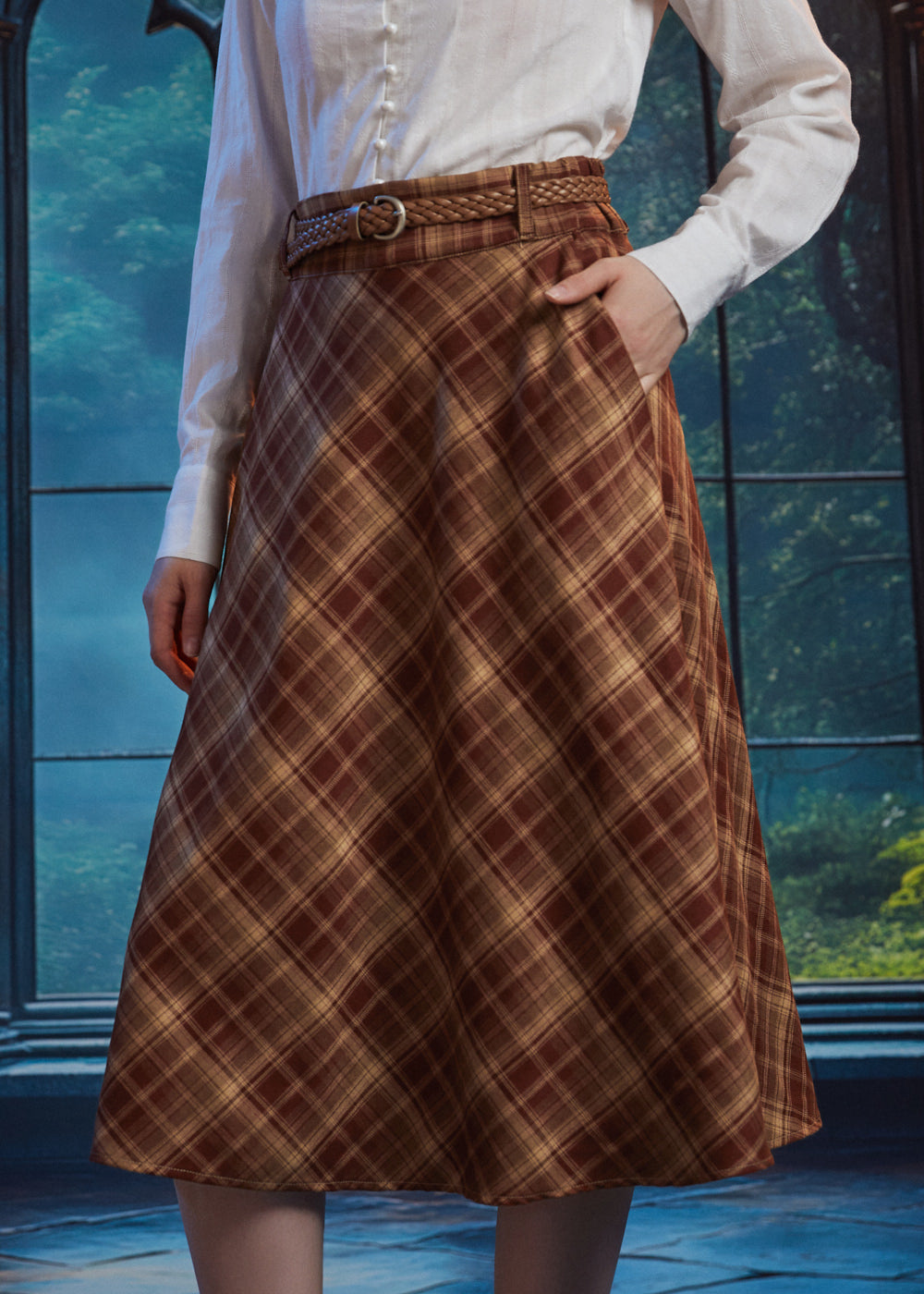 Woman wearing a brown plaid high-waisted midi skirt with braided belt, A-line silhouette and hand in side pocket