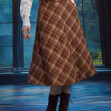 Woman wearing a vintage-inspired brown plaid A-line midi skirt with braided waist belt and burgundy lace-up boots