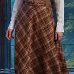 Front close-up of woman wearing the Brown Study plaid midi skirt showing diagonal bias-cut plaid and braided belt
