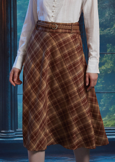 Front close-up of woman wearing the Brown Study plaid midi skirt showing diagonal bias-cut plaid and braided belt