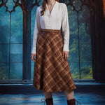 Full-length view woman wearing ivory vintage-inspired blouse with brown plaid midi skirt and lace-up boots