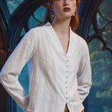 Three-quarter view of woman wearing ivory pearl button blouse showing V-neck shawl collar, long sleeves and dobby stripe texture