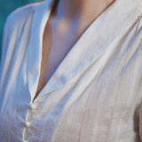 Close-up of ivory cotton blend blouse showing shawl collar, V-neckline, pearl-style buttons and vertical dobby stripe texture