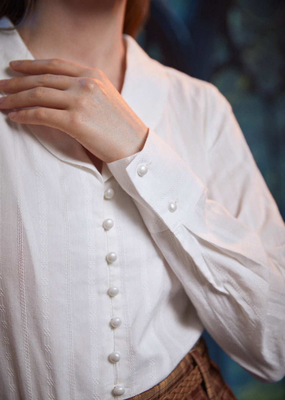 Close-up of ivory blouse showing pearl-style front buttons, textured dobby stripes and button cuff