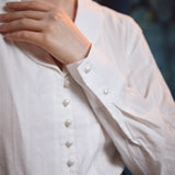 Close-up of ivory blouse showing pearl-style front buttons, textured dobby stripes and button cuff