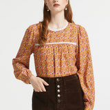 Woman wearing brown ditsy floral blouse with gathered yoke, lace trim and button cuff sleeves
