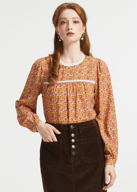 Woman wearing brown ditsy floral blouse with gathered yoke, lace trim and button cuff sleeves