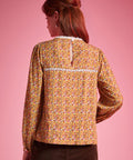 Back view of woman wearing brown floral blouse with white lace yoke trim and keyhole closure
