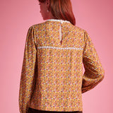 Back view of woman wearing brown floral blouse with white lace yoke trim and keyhole closure