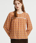 Woman wearing brown floral prairie blouse with long sleeves and lace-trimmed gathered yoke