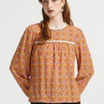 Woman wearing brown floral prairie blouse with long sleeves and lace-trimmed gathered yoke