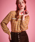 Woman wearing brown ditsy floral long sleeve blouse with white lace neckline and gathered yoke