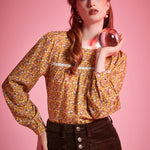 Woman wearing brown ditsy floral long sleeve blouse with white lace neckline and gathered yoke