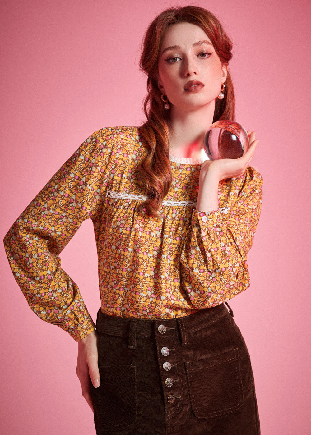 Woman wearing brown ditsy floral long sleeve blouse with white lace neckline and gathered yoke
