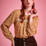 Woman wearing brown ditsy floral long sleeve blouse with white lace neckline and gathered yoke