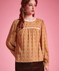 Front view of woman wearing brown floral long sleeve blouse with white lace neckline and gathered yoke