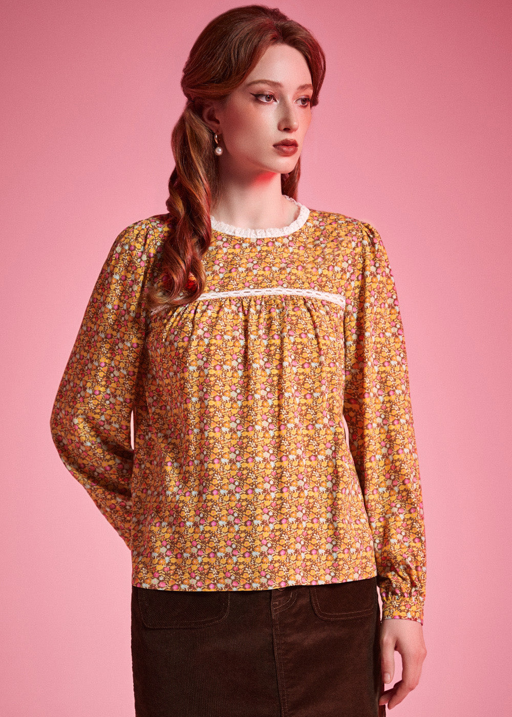 Front view of woman wearing brown floral long sleeve blouse with white lace neckline and gathered yoke