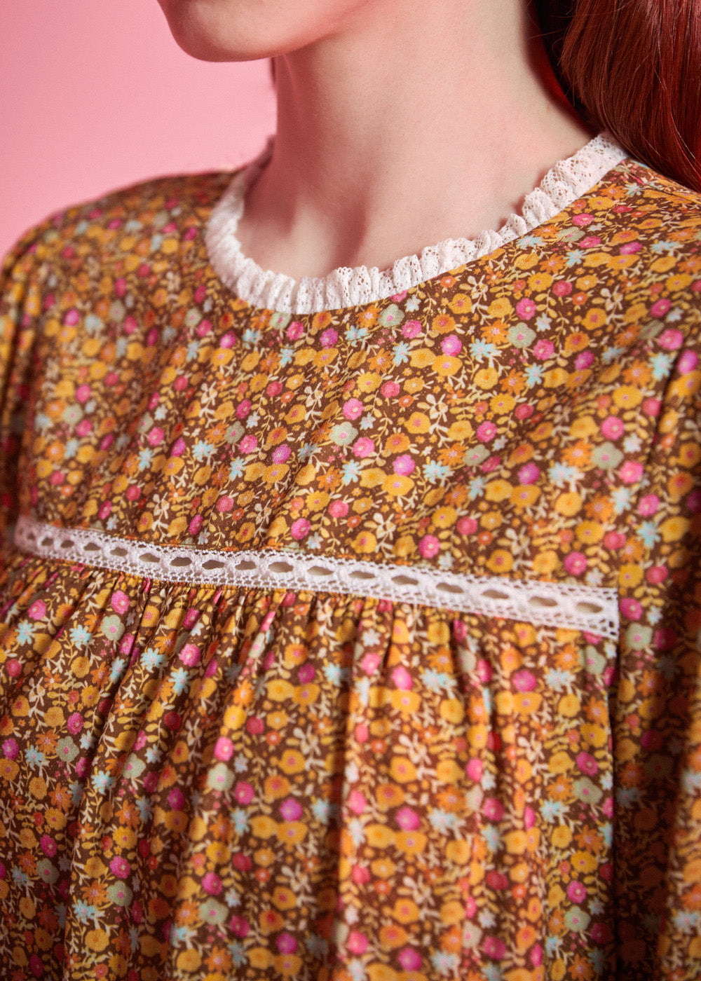 Close-up of brown ditsy floral blouse showing white ruffled neckline, lace yoke trim and gathered front