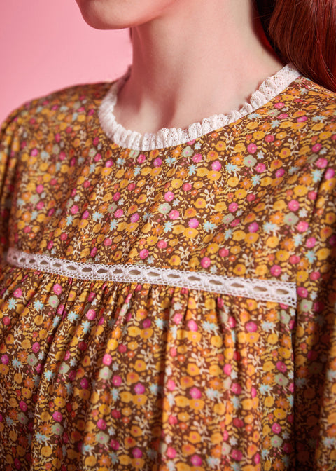 Close-up of brown ditsy floral blouse showing white ruffled neckline, lace yoke trim and gathered front
