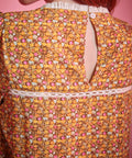 Close-up back view of brown floral blouse showing button keyhole closure and white lace trim