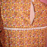 Close-up back view of brown floral blouse showing button keyhole closure and white lace trim
