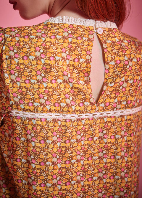 Close-up back view of brown floral blouse showing button keyhole closure and white lace trim
