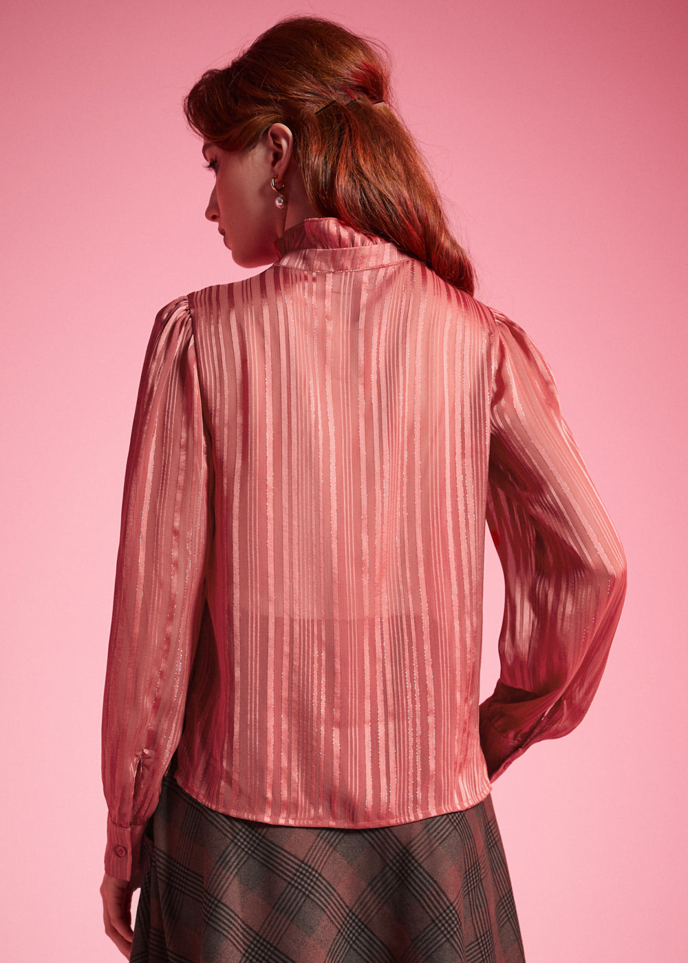 Back view of woman wearing dusty rose striped long sleeve blouse showing the semi-sheer woven fabric and ruffled high collar