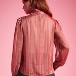 Back view of woman wearing dusty rose striped long sleeve blouse showing the semi-sheer woven fabric and ruffled high collar