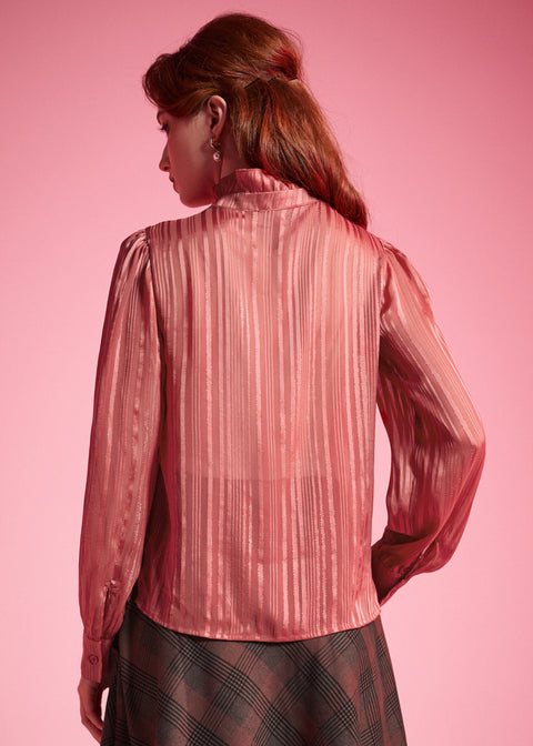 Back view of woman wearing dusty rose striped long sleeve blouse showing the semi-sheer woven fabric and ruffled high collar